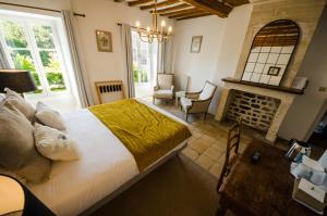 1 dormitorio con 1 cama grande y chimenea en Ferme du Loucel, en Colleville-sur-Mer