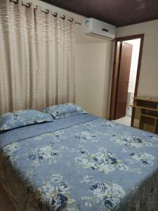 Schlafzimmer mit einem Bett mit blauer Decke in der Unterkunft Suíte Maciel in Foz do Iguaçu