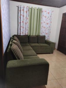 ein Wohnzimmer mit grünem Sofa und Vorhängen in der Unterkunft Suíte Maciel in Foz do Iguaçu