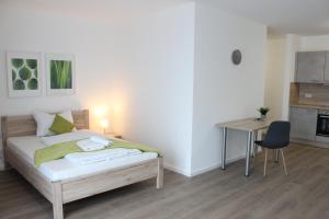 een slaapkamer met een bed, een tafel en een bureau bij greenpartment Boardinghousehotel Kelheim in Kelheim