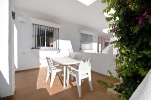 ein weißes Esszimmer mit einem weißen Tisch und Stühlen in der Unterkunft Apartamento Calas Sancti Petri in Novo Sancti Petri