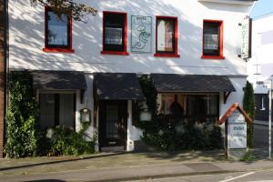 a white building with red windows on a street at Hotel Anchovis in Mönchengladbach
