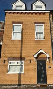 a brick building with a black door and three windows at Beautiful 6 bedroom home close to city centre with free parking in Liverpool