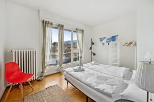 um quarto com 2 camas e uma cadeira vermelha em Central Apartment for City Explorers 222 em Zürich