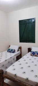 2 camas en una habitación con ventana verde en Casa do Renato Lençóis en Lençóis