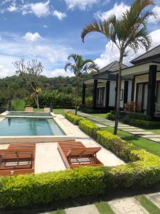 a villa with a swimming pool with two lounge chairs at Bali Astetic Villa and Hot Spring in Kintamani