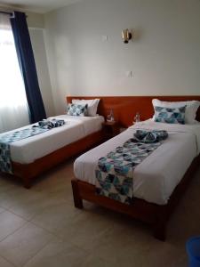 1 dormitorio con 2 camas y ventana en Sai Inn Eldoret en Eldoret