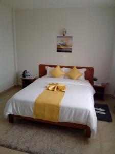 Un dormitorio con una gran cama blanca con almohadas amarillas. en Sai Inn Eldoret, en Eldoret