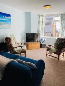 a living room with a blue couch and two chairs at Kearney Cottage - Artist's Retreat in Portland