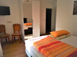 KattenesにあるBio-Ferienweingut Leyendeckerのベッドルーム1室(オレンジ色の枕と鏡付きのベッド1台付)