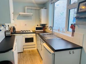 a kitchen with white cabinets and a black counter top at Kearney Cottage - Artist's Retreat in Portland