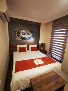 a bedroom with a large bed with red pillows at ADOR TROIA HOTEL in Çanakkale