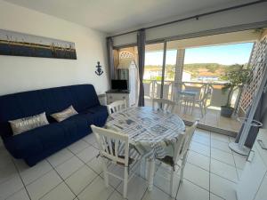 sala de estar con sofá azul, mesa y sillas en Le Surf, en Mimizan-Plage