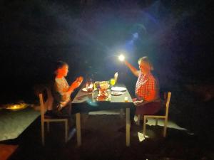 曼度的住宿－Mandhoo Inn，两个女人晚上坐在桌子上,灯火通明