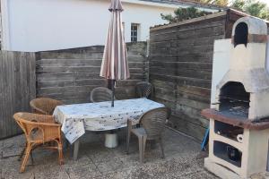 eine Terrasse mit einem Tisch und einem Backofen im Freien in der Unterkunft Spacious quiet nest with garden near the sea in La Tranche-sur-Mer