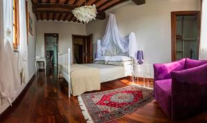 a bedroom with a white bed and a purple couch at Leopoldina L'Orto in Arezzo
