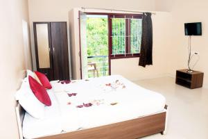 a white bed in a room with a window at Grass dew in Yercaud