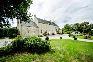 an old stone house with a car parked in the driveway at Ferme du Loucel in Colleville-sur-Mer