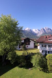 una casa en un campo con montañas en el fondo en Ferienwohnung AlpspitzNest, en Garmisch-Partenkirchen