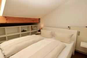 uma cama branca com almofadas brancas num quarto em Central Pearl em Garmisch-Partenkirchen