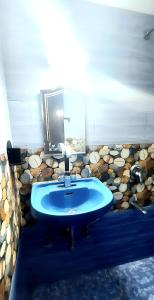 uma casa de banho com um lavatório azul e uma parede de pedra em Casa Cottage Benaulim em Benaulim