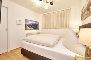 a white bedroom with a bed and a window at BergJuwel in Garmisch-Partenkirchen
