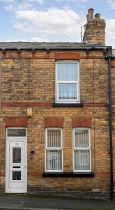 a brick house with three windows and a white door at Sandy House in Scarborough