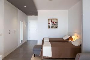 a hotel room with two beds and a chair at RentOnTheBeach Studio 2 in Los Cristianos