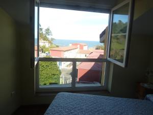 Habitación con ventana, cama y vistas. en Apartamento Playa de La Atalaya, en Ribadesella