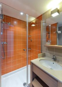 y baño con azulejos de color naranja, ducha y lavamanos. en Villages Clubs du Soleil - LES 2 ALPES, en Les Deux Alpes