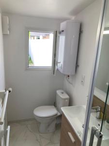 La salle de bains blanche est pourvue de toilettes et d'une fenêtre. dans l'établissement Dépendance privative et indépendante Le Cocon, à Montgeron
