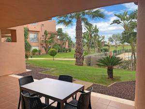 d'une terrasse avec une table, des chaises et des palmiers. dans l'établissement Ona Mar Menor - The Residences, à Torre-Pacheco