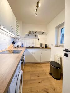 eine Küche mit weißen Geräten und Holzböden in der Unterkunft Kirchturm-Panorama - Apartment mit Balkon im Herzen von Braunschweig in Braunschweig