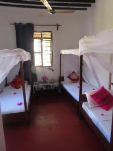 a room with three bunk beds and a window at Jacob's Inn Jambiani in Jambiani