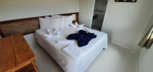 uma cama branca com toalhas brancas e arcos azuis em Hotel Escarpas do Lago Capitolio em Capitólio