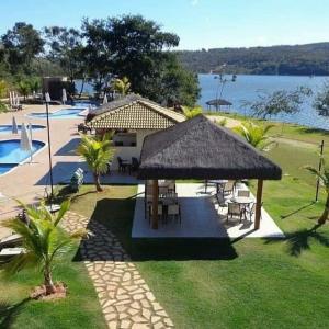 a pavilion with tables and chairs next to a pool at ALDEIA do LAGO Caldas Novas Lindo Apt com Cozinha Mobília Nova Pode Levar Bebidas na Área das Piscinas in Caldas Novas