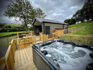 a hot tub on a deck next to a building at Meadow Retreat in Rhayader
