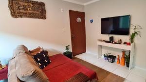 sala de estar con sofá y TV de pantalla plana en Apartamento a 15 minutos da praia, en Florianópolis