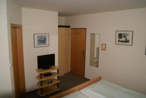ein Schlafzimmer mit einem Bett und einem Fernseher auf einem Regal in der Unterkunft Pension Sielmöwe in Neuharlingersiel