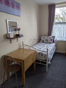 1 dormitorio con cama, mesa y escritorio en Cleasewood Guest House, en Great Yarmouth