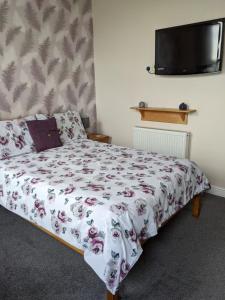 a bedroom with a bed with a floral bedspread at Cleasewood Guest House in Great Yarmouth
