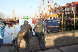 a statue of two men sitting on a wall next to a harbor at Pension Sielmöwe in Neuharlingersiel