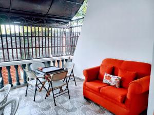 a living room with an orange couch and a table and chairs at CerroAly in Santiago de los Caballeros