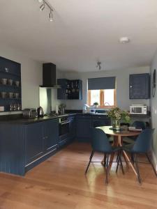 a kitchen with blue cabinets and a table and chairs at The Hen Den in Hopton Cangeford