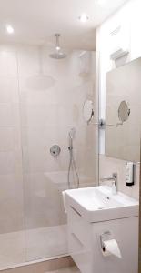 baño blanco con ducha y lavamanos en Hotel Schrenkhof, en Unterhaching