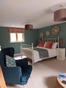 a bedroom with a bed and a chair at The Hen Den in Hopton Cangeford