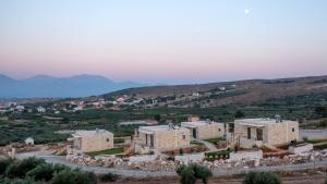 un ensemble de bâtiments sur une colline avec des montagnes en arrière-plan dans l'établissement Alagni Cretan Resort, à Stíronas