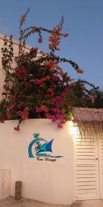 a sign on the side of a building with flowers at Ras Village in Rasdu