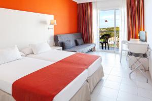 Habitación de hotel con cama, sofá y escritorio en Minura Sur Menorca & Waterpark, en Punta Prima