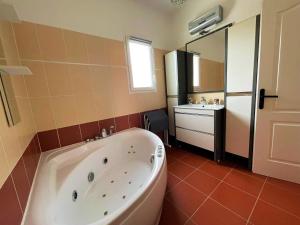 a bathroom with a large tub and a sink at Villa au calme tout confort in Lapalud